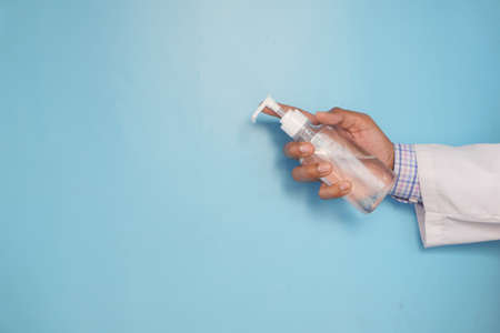 close up of doctor hand holding sanitizer liquid on blue with copy spaceの写真素材