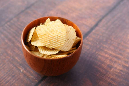 Bowl with tasty potato chips on wooden background .の写真素材