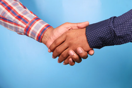 two people hand shake against blue background,
