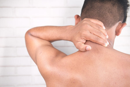man suffering from neck pain at home.