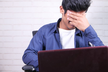 Close up of sad man covering face with hand.