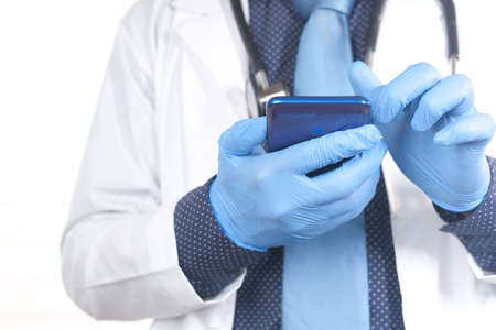 doctors hand in protective gloves using a smartphone.の写真素材