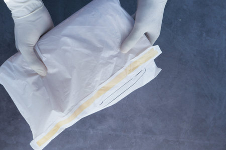 hand in latex gloves holding white paper bubble envelope for postal ship.