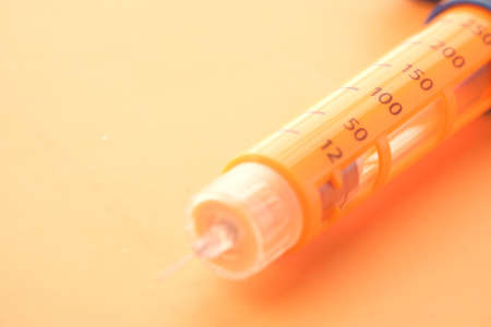 Insulin pens on orange background, close upの写真素材