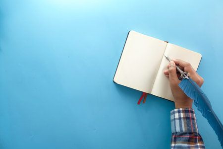 man hand writing with fountain pen on notepad on blue background