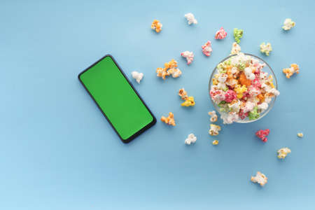 top view of smart phone and popcorn on blue backgroundの写真素材