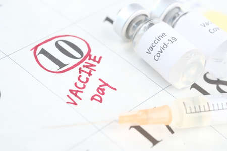 vaccine day concept glass ampoule with vaccine and syringe on calendarの写真素材