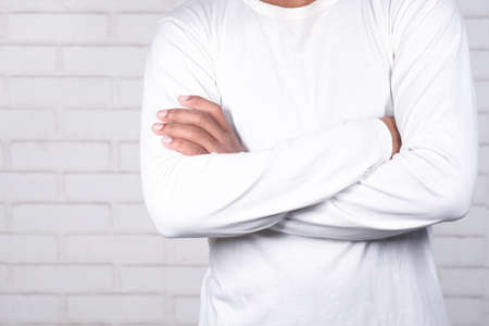 unrecognized man with casual dress arm crossed standing against white wall ,の写真素材