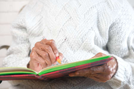 enior women hand writing on notepad.の写真素材