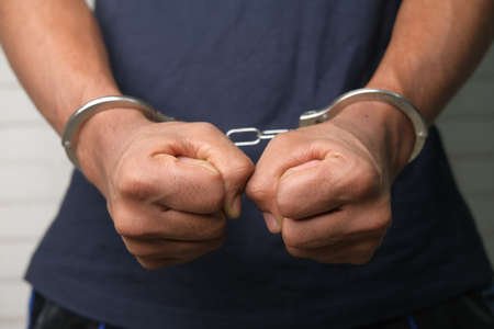 mans hand with handcuff on black background.の写真素材
