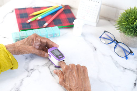senior women hand using pulse oximeter on table