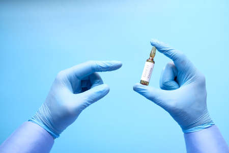 hand in latex gloves holding glass ampoule vaccine, with copy spaceの写真素材
