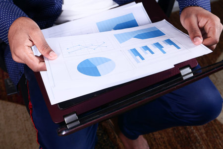 young man sitting on a chair with laptop analyzing financial dataの写真素材