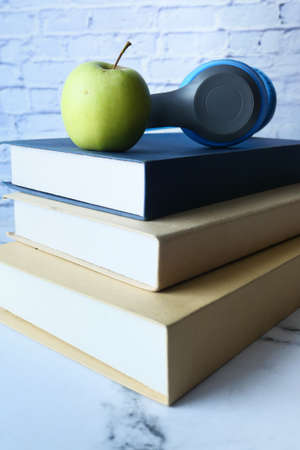 stack of books, apple and headphone on tableの写真素材