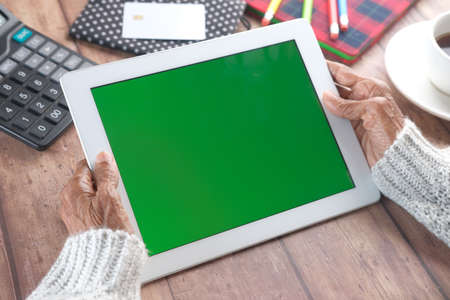 senior women holding digital tablet with green screen on tableの写真素材