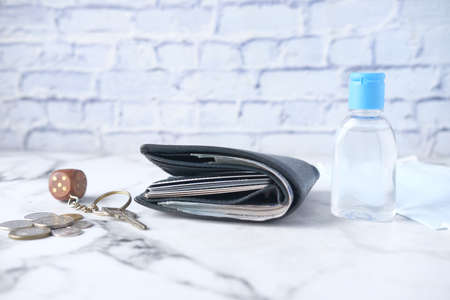 Close up of cash in wallet, hand sanitizer, key and coins on tableの写真素材