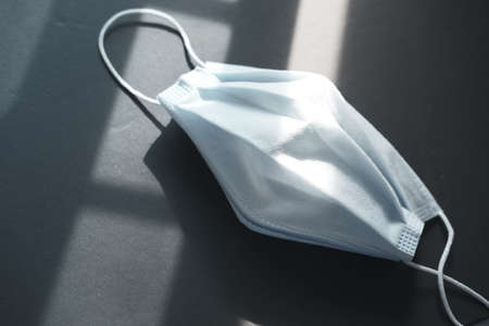 Close up of blue surgical masks and sun light on black backgroundの写真素材