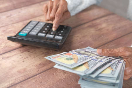 senior women holding us dollar cash and using calculator, selective focusの写真素材