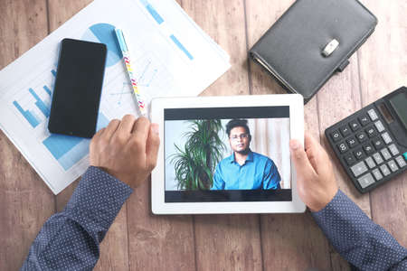 businessman holding digital tablet discussing ideas in video conferenceの写真素材