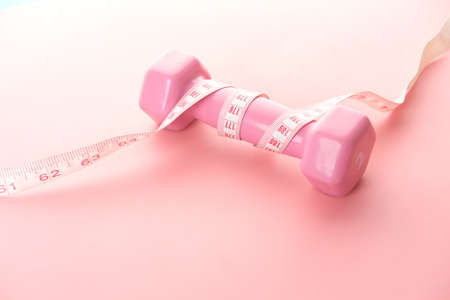 Fitness concept with dumbbell and measurement tape on white backgroundの写真素材
