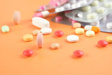 Close up of many colorful pills and capsules on orange background