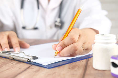 female doctor hand writing prescription on desk, close up.の写真素材