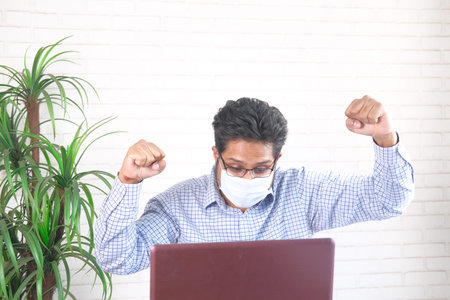 Businessman in face mask working on laptop