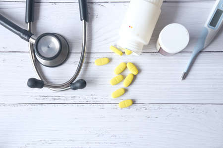 stethoscope and pills container on wooden backgroundの写真素材