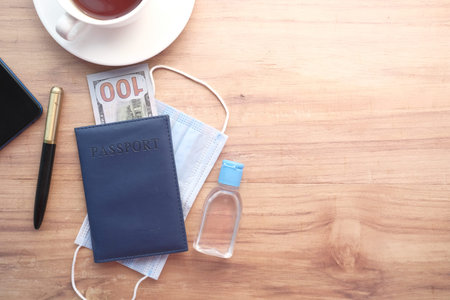protective mask, hand sanitizer and blue color passport on table