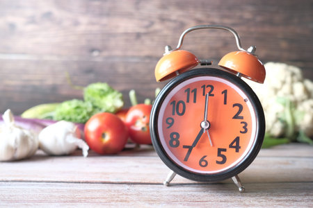 alarm clock and fresh vegetables on table with copy spaceの写真素材