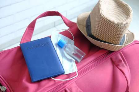 Travel suitcase with a mask, passport and hand sanitizer.