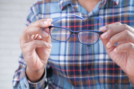Close up of man hand holding eyeglass in dark.の写真素材