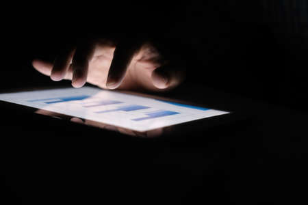 mans hand working on digital tablet at office desk, using self created chartの写真素材