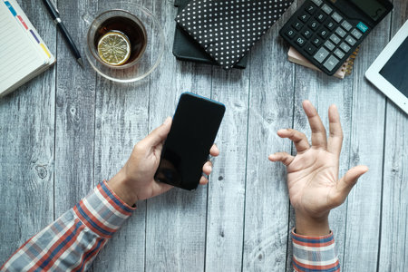 top view of young man using smart phone on office deskの写真素材
