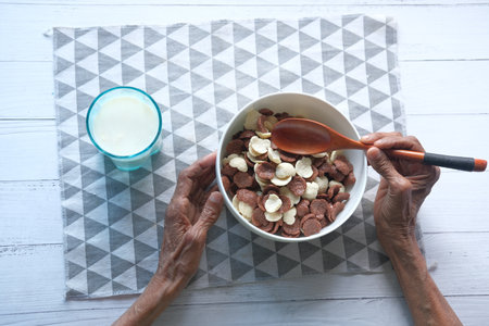 Top view of senior women eating chocolate corn flakes in a bowlの写真素材