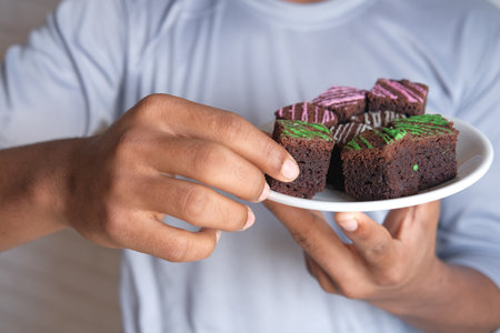 young man eating brownie on plateの写真素材