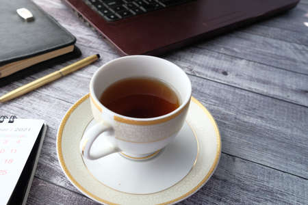 close up of green tea with laptop and office stationary on wooden deskの写真素材
