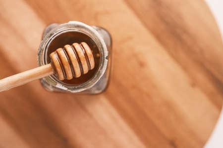 close up of fresh honey with spoon isolated on wooden tableの写真素材