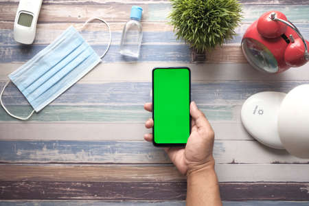 flat composition of smart phone, mask, thermometer and sanitizer on tableの写真素材