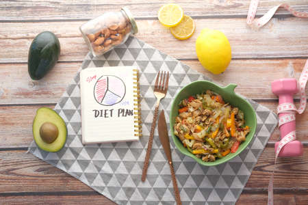 Diet plan with healthy meal and dumbbell on wooden backgroundの写真素材