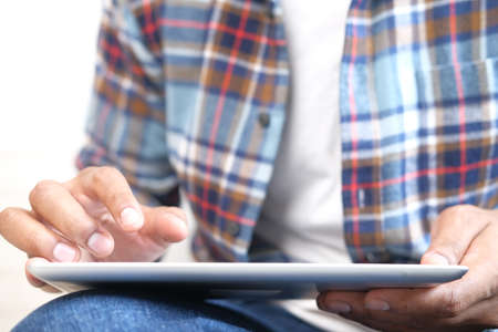 Work from home concept, young man working on digital tablet sitting on floorの写真素材