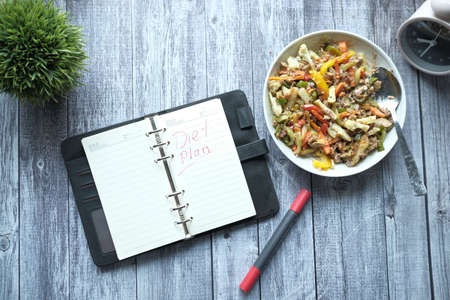 hand writing text diet on plan on notepad with fresh cooked salad on plateの写真素材