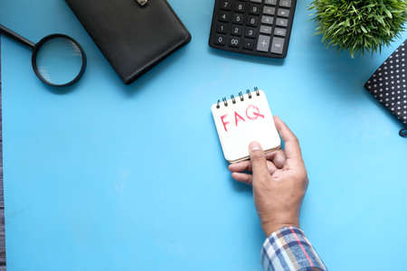 hand drawing text FAQ on notepad on blue backgroundの写真素材