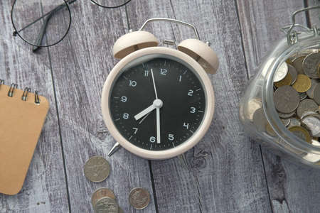 old alarm clock , notepad and coins on wooden tableの写真素材