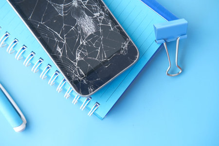 Top view of broken smart phone on color background