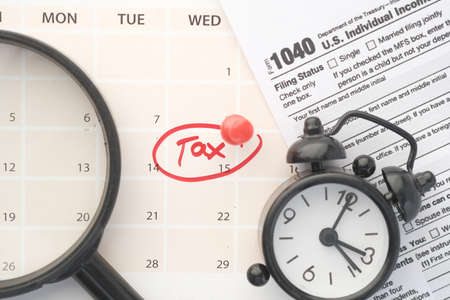 tax day concept with red circle on calendar date and tax return on tableの写真素材