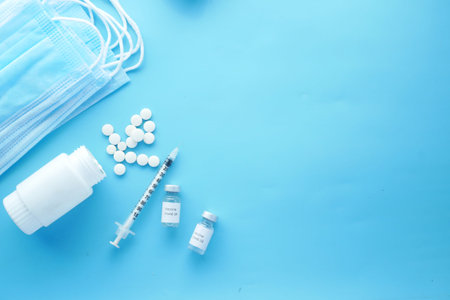 coronavirus vaccine . medical pills , mask and syringe on blue background