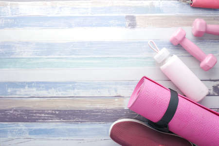 pink color dumbbell, exercise mat and water bottle on wooden backgroundの写真素材