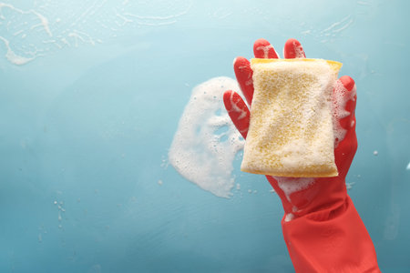 hand with rubber gloves holding sponge