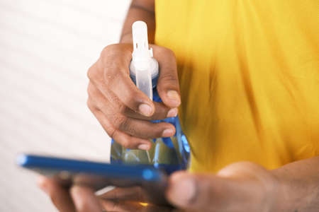cleaning mobile phone display with sanitizer liquidの写真素材